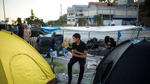 Ein Kind sitzt am Rande einer Straße zwischen zwei Zelten. Die Situation war schon vor dem Brand angespannt - nun sind die Menschen noch mittelloser.