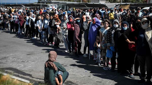 Über den gesamten Supermarkt-Parkplatz stehen Migranten Schlange, um Lebensmittel und Wasser zu bekommen.