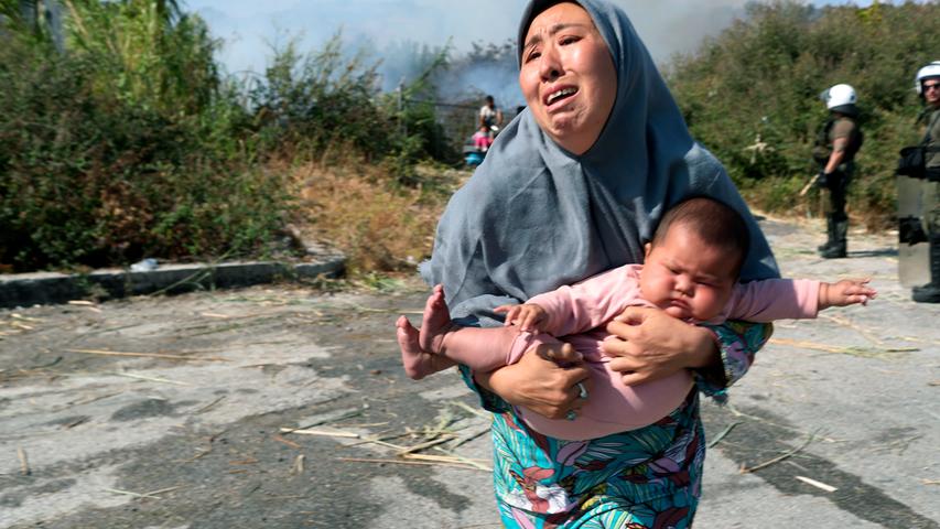 Nach den Bränden in dem überfüllten Lager Moria: Eine Frau hält ihr Baby auf der Flucht vor einem kleinen Feuer auf einem Feld in der Nähe der Stadt Mytilene. 