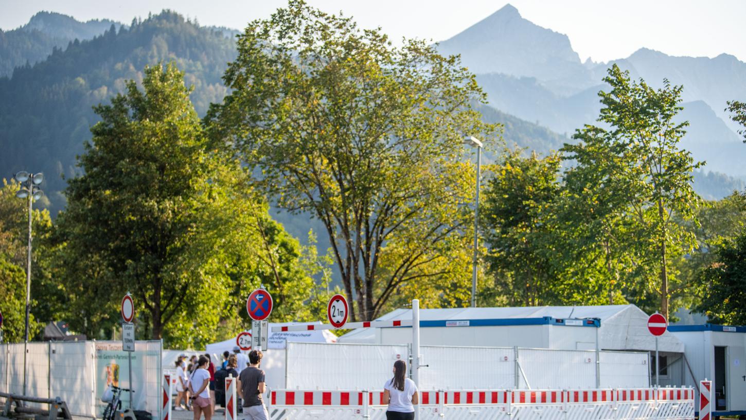 Menschen stehen Schlange vor dem Corona-Testzentrum der Gemeinde. Nach einem heftigen Corona-Ausbruch im oberbayerischen Garmisch-Partenkirchen ist noch unklar, mit welchen Konsequenzen die mutmaßliche Verursacherin rechnen muss.