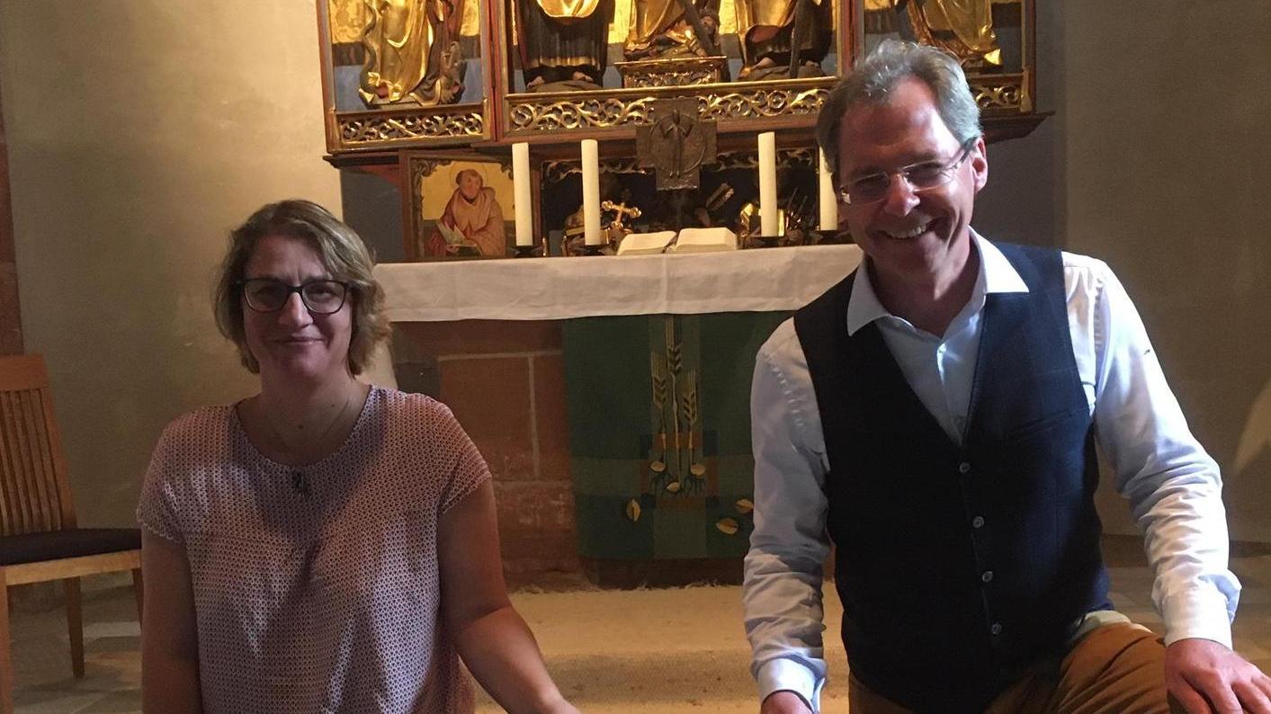 Pfarrerin Marion Fraunholz und Archäologe Thomas Liebert zeigen eine Dokumentation der geöffneten Stelle vor dem Altar.