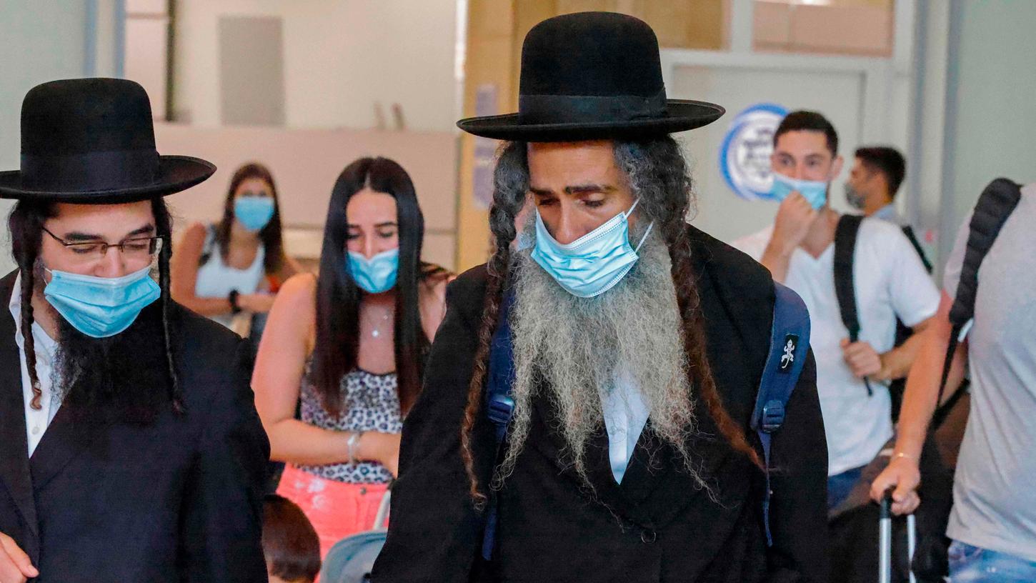 Ultraorthodoxe Juden mit Gesichtsmasken am Flughafen in Tel Aviv: Diese Gruppe ist laut Statistik vom Corona-Virus besonders betroffen.