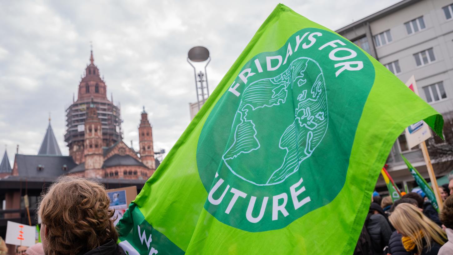 Rheinland-Pfalz, Mainz: Ein Teilnehmer steht mit einer Flagge mit dem Aufdruck "Fridays For Future" bei einer Demonstration vor dem Dom. Am Freitag, 25. September, finden in Mainz wieder Aktionen des Bündnisses statt.