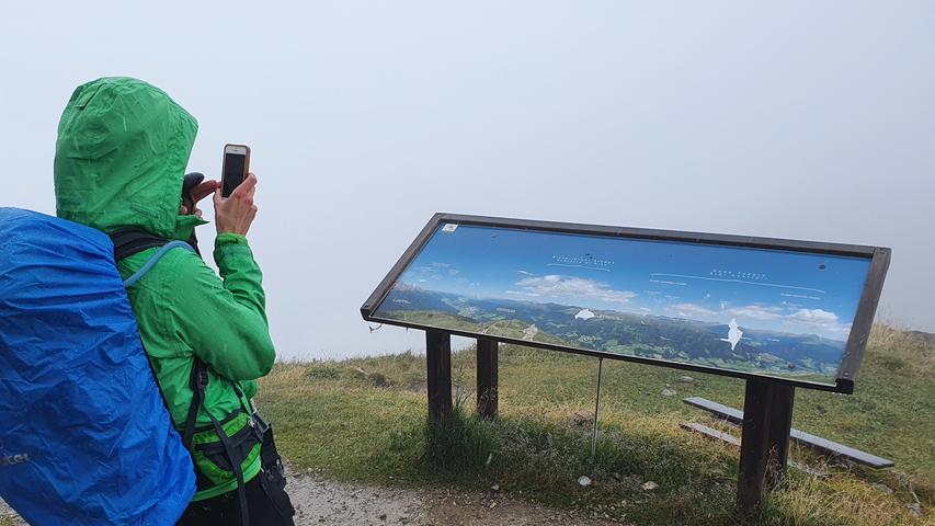 Der Gipfel des Helm hüllt sich in dichten Nebel. Eine Tafel zeigt das Panorama, das sich an schönen Tagen bietet.