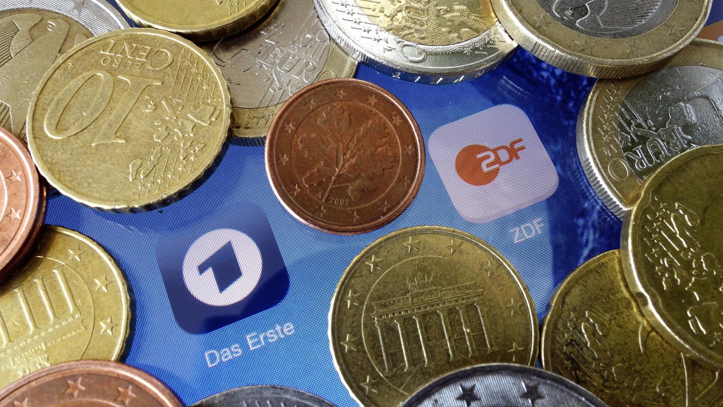 Euromünzen liegen neben den Logos der Apps von ARD und ZDF: Öffentlich-rechtliche Sender sind auf den Rundfunkbeitrag angewiesen. Aber darf man diesen auch in bar zahlen?