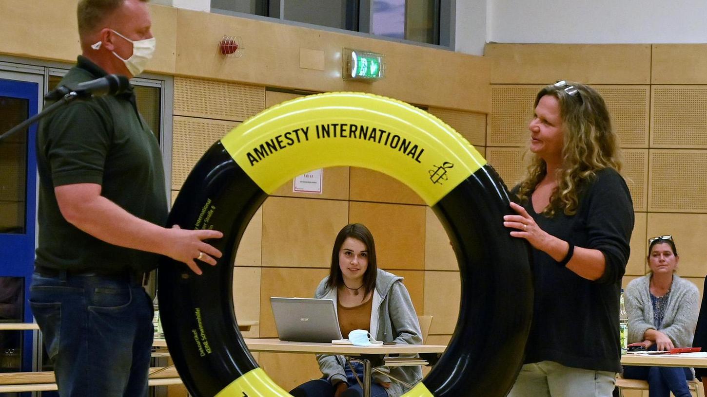 Kathrin Görlitz von der Flüchtlingsinitiative Bubenreuth übergab Bürgermeister Norbert Stumpf symbolisch einen Rettungsring von Amnesty International.