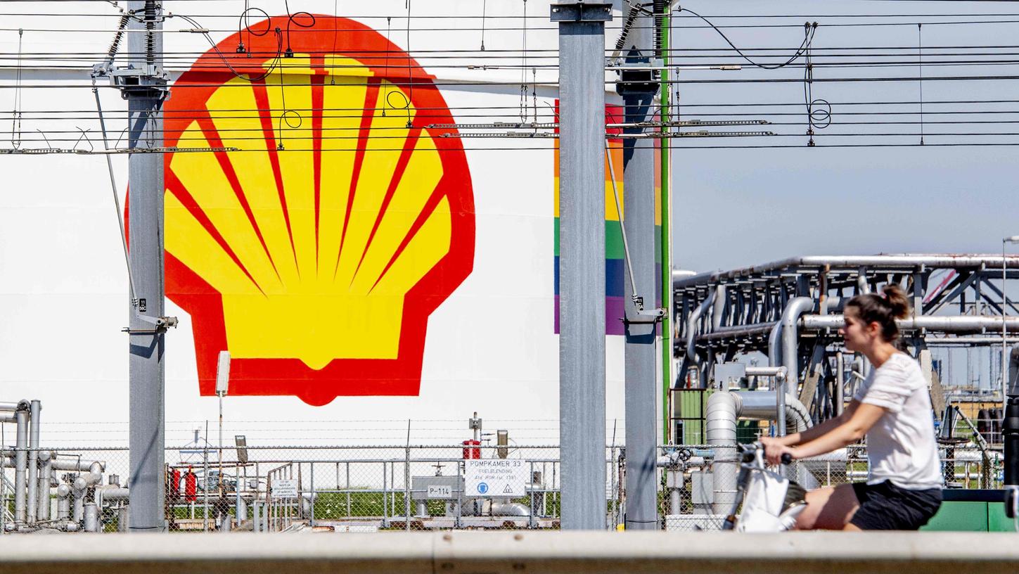 Eine Frau fährt mit dem Fahrrad an einem Tank mit dem Shell-Logo vorbei: Der Konzern will die Kosten drücken und mehrere tausend Stellen streichen.