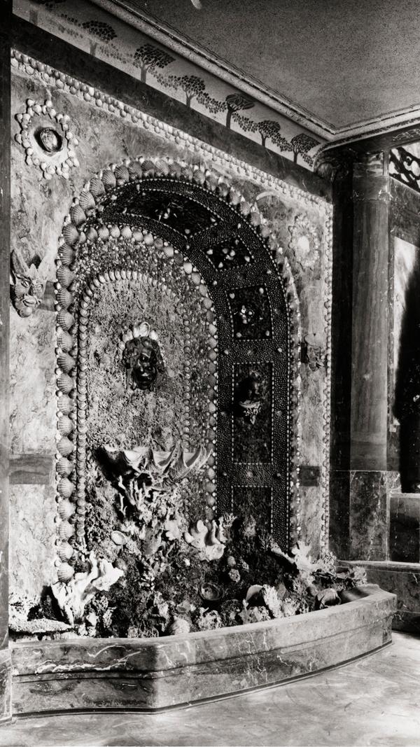 Natürlich ließen die Umgestaltungspläne der Nazis keinen Raum für den kunstvoll verspielten Muschelbrunnen im Parkettfoyer. In der Eile, in der der von Hitler befohlene und insgesamt auf niedrigem Qualitätsniveau gestaltete Umbau durchgezogen wurde, schlug man ihn einfach ab und zog eine Mauer davor hoch. Bei der bislang letzten Renovierung des Innenraums entdeckte man ihn wieder und machte ein Loch in die Wand, durch das man die Reste des Brunnens erahnen und befühlen kann.