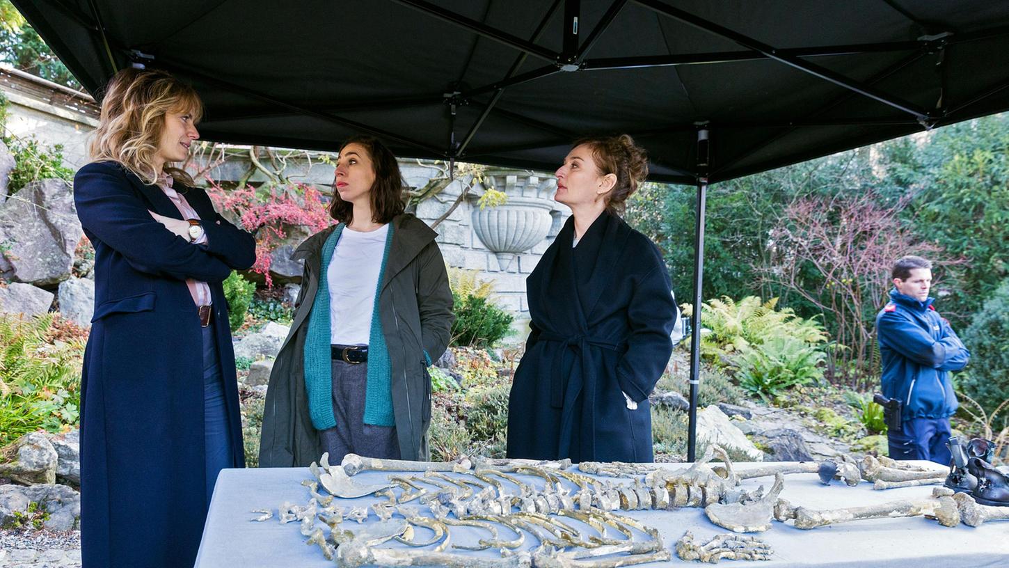Die beiden Ermittlerinnen Isabelle Grandjean (Anna Pieri Zuercher) und Tessa Ott (Carol Schuler) sowie Staatsanwältin Anita Wegenast (Rachel Braunschweig) mit einem Skelettfund.
Die beiden Ermittlerinnen Isabelle Grandjean (Anna Pieri Zuercher) und Tessa Ott (Carol Schuler) sowie Staatsanwältin Anita Wegenast (Rachel Braunschweig) mit einem Skelettfund.