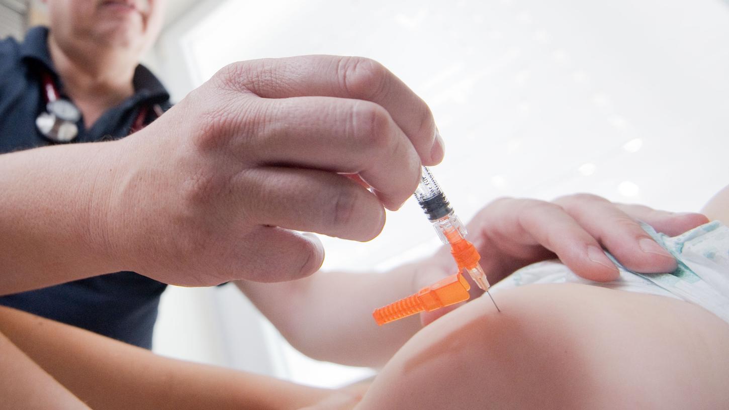 Ein Kinderarzt impft ein einjähriges Kind in den Oberschenkel mit dem Impfstoff Priorix (Lebendvirusimpfstoff gegen Masern, Mumps und Röteln). 