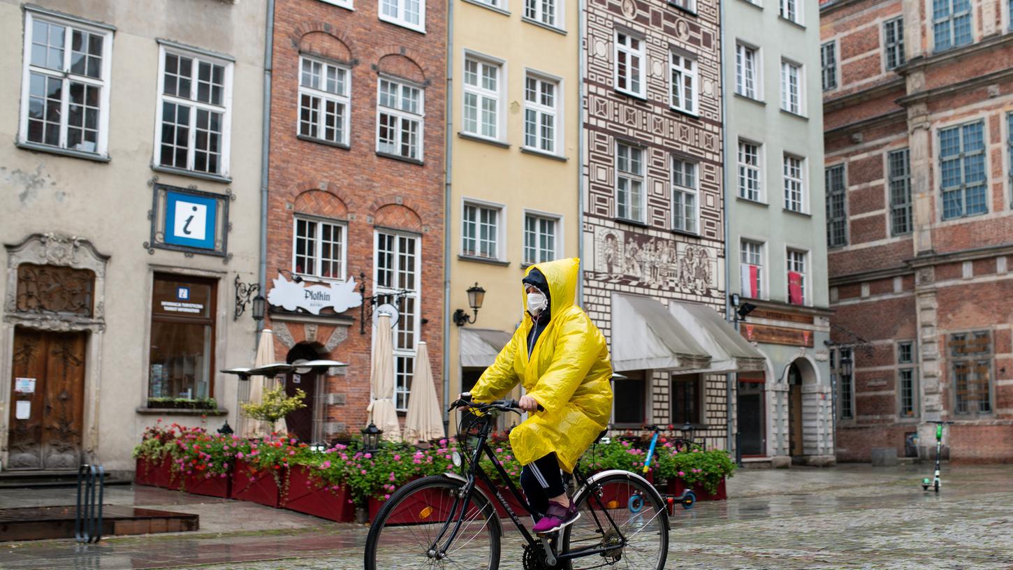 Eine Frau mit Mund-Nase-Schutz fährt auf der Dluga-Straße Rad. Die Bundesregierung hat die Nachbarländer Polen und Schweiz, fast ganz Österreich und große Teile Italiens mit Wirkung ab dem kommenden Samstag zu Corona-Risikogebieten erklärt.