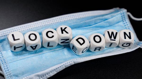 Das Foto zeigt einen blauen Mundschutz auf dem Würfel liegen, die das Wort Lockdown bilden, Maske, Gesichtsmaske, Mund-