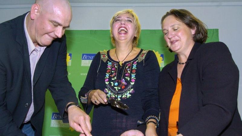Die Landesvorsitzenden der bayerischen Grünen, Sepp Daxenberger (links), Theresa Schopper (rechts) schneiden 2004 gemeinsam mit der Bundesvorsitzenden von Bündnis 90/Die Grünen, Claudia Roth eine Torte zum 25-jährigen Bestehen des Landesverbandes an. Daxenberger hat hier schon die erste Chemotherapie hinter sich gebracht.