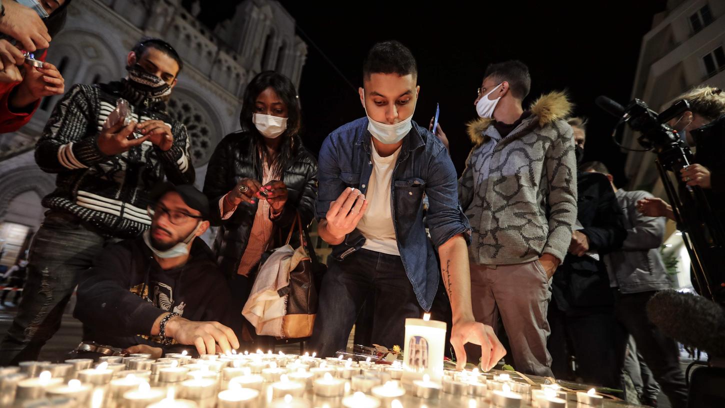 Nach der Messerattacke zünden Menschen auf der Straße vor der Kirche Notre Dame Kerzen für die Opfer an.
