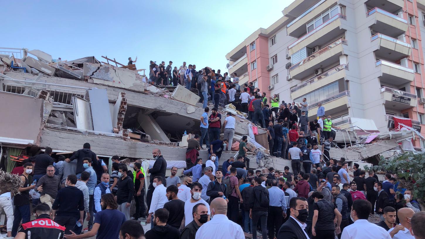 Rettungskräfte und Anwohner versuchen in Izmir Menschen, die in den Trümmern eines eingestürzten Gebäudes eingesperrt sind, zu erreichen.