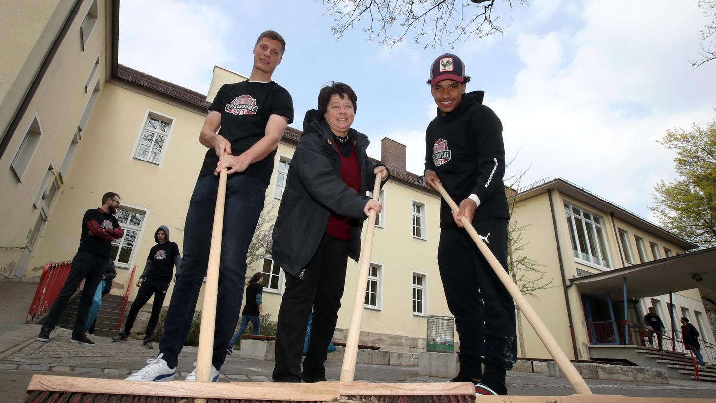 Bei der Aktion "Spielräume" schwangen Club-Spieler 2019 den Besen. Patrick Erras (links) und Matheus Pereira, die hier mit Susanne Kaufmann von der Grundschule Bismarckstraße zu sehen sind, haben den Verein zwar inzwischen verlassen, das Projekt aber soll wiederaufgelegt werden.  