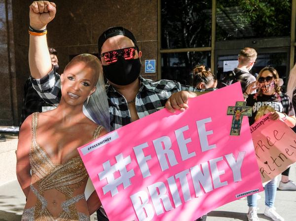 Ein Fan und Unterstützer von US-Popsängerin Britney Spears hält bei einer Protestveranstaltung vor dem Stanley Mosk Gerichtsgebäude neben einem Spears-Pappaufsteller ein Plakat mit der Aufschrift "#Free Britney".