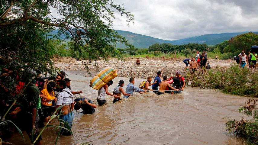 Weil die offizielle Grenze zwischen Kolumbien und Venezuela wegen der Corona-Pandemie geschlossen ist, versuchen viele in Kolumbien gestrandete Bürger Venezuelas, über die "grüne Grenze" in ihre Heimat zu gelangen. Hier überqueren sie mithilfe eines Seiles den Fluss Tachira.