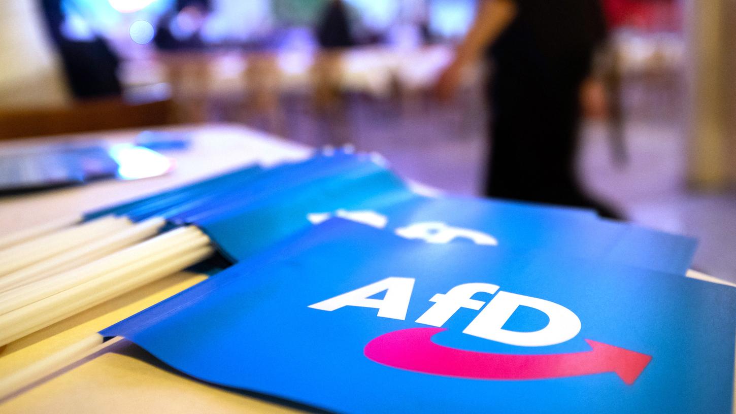 Fähnchen mit dem Logo der AfD liegen beim Landesparteitag der AfD Bayern auf einem Tisch. 