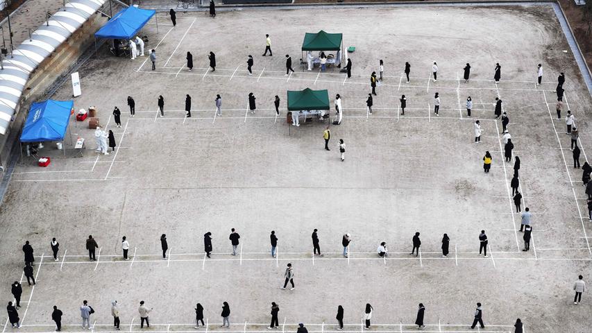 Südkoreanische Studenten stehen im Hof einer Universität in Seoul Schlange, um sich an einem Corona-Massentest zu beteiligen. Die Linien auf dem Boden markieren den Abstand, den sie untereinander halten sollen.  