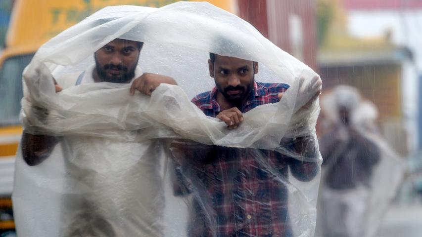 Zwei Männer haben sich in der indischen Provinz Chennai mit einer Plastikplane umhüllt, um sich vor dem Regen zu schützen, den der Zyklon "Nivar" mit sich führte, als er dort auf die Küste zuhielt.