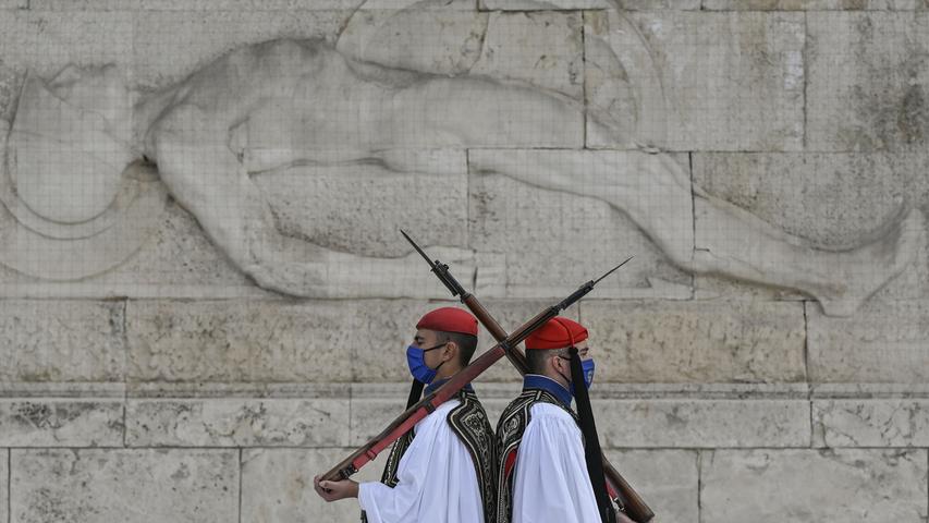 Zwei Angehörige der griechischen Präsidentengarde patrouillieren in Athen mit Gesichtsmaske und Gewehr über der Schulter vor dem Grabmal des unbekannten Soldaten.