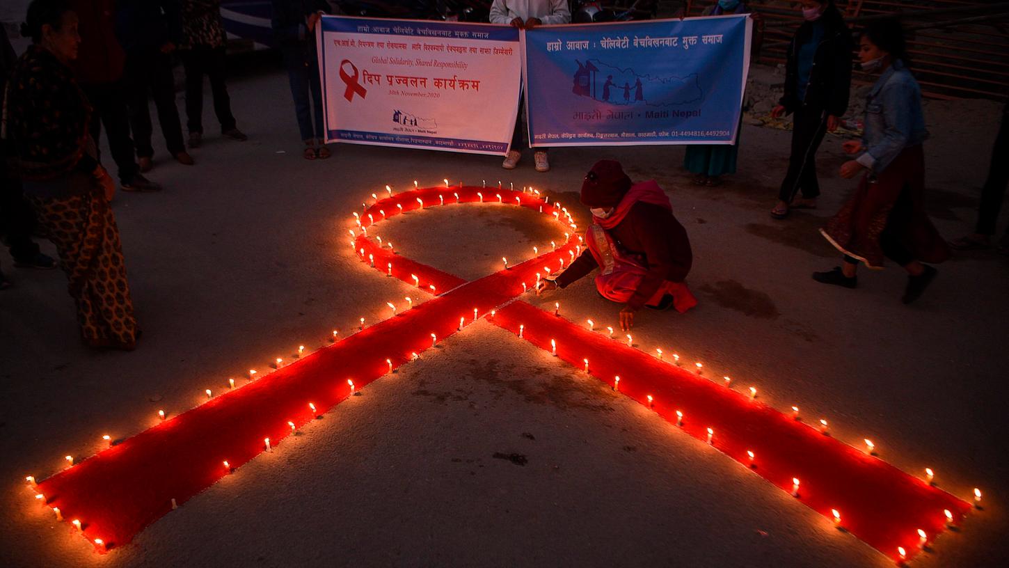 Zum Welt-Aids-Tag an diesem 1. Dezember erinnern vielerorts Blumen- oder Kerzenarrangement in Form der roten Schleife an die Betroffenen und Opfer der Immunschwächekrankheit.