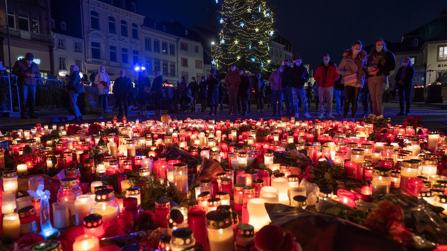 Menschen gedenken am Abend vor der Porta Nigra für die Opfer einer Amokfahrt und stellen Kerzen ab.
