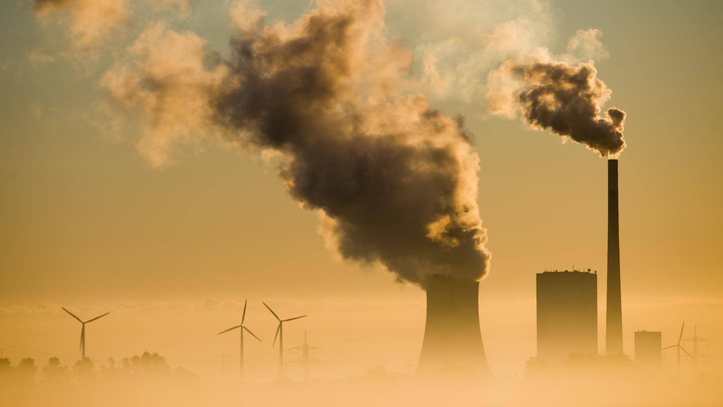 Windkraftanlagen und ein Kohlekraftwerk: Letzteres sorgt dafür, dass die Kohlenstoffdioxid-Emissionen nicht so schnell zurückgehen wie von Forschern empfohlen.