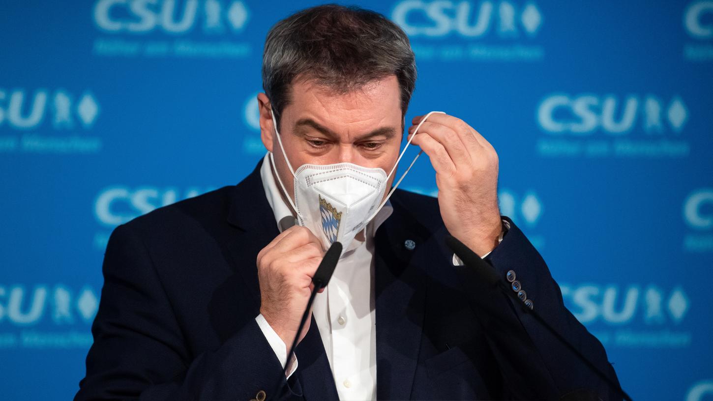 Markus Söder (CSU) zieht nach einer Pressekonferenz seinen Mund-Nasen-Schutz auf. 