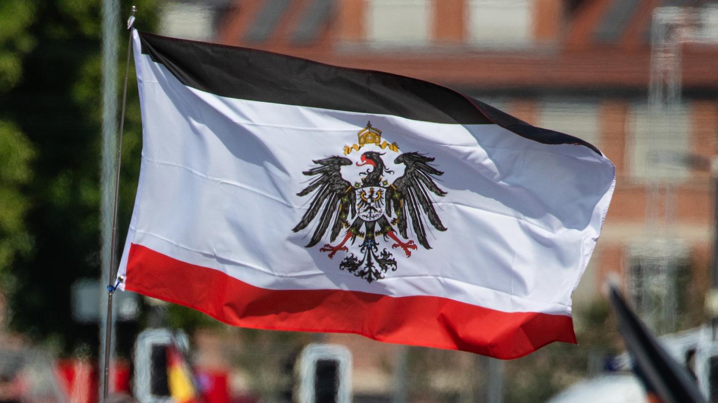 Ein Teilnehmer schwingt auf dem Cannstatter Wasen in Stuttgart bei einer "Querdenker"-Protestkundgebung eine Reichsflagge.