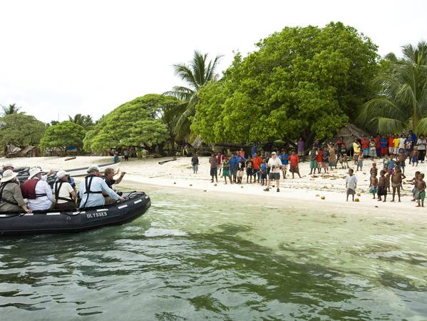 Touristen landen in Papua-Neuguinea mit dem Boot bei Einheimischen an.
