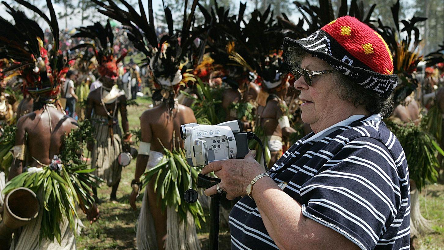 Eine amerikanische Touristin filmt während einer Urlaubsreise durch Papua-Neuguinea ein Kulturfestival von Einheimischen.