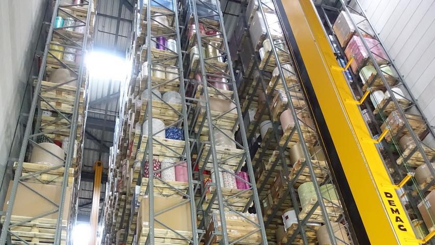 In dem modernen, computergesteuerten Hochlager stapeln sich gewaltige Geschenkpapierrollen in Regalen über 30 Meter.
