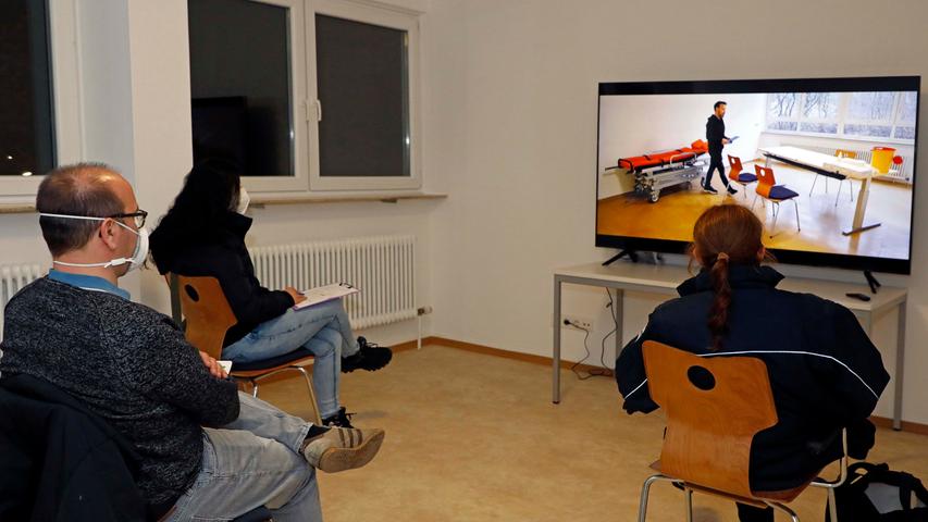 In einem der Räume im Erdgeschoss steht ein großer Flachbildschirm. Darauf ist ein Video zu sehen, das Fabian Hofmann, ASB-Azubi aus Oesdorf, mit seinem Smartphone gedreht hat. "Der offizielle Film liegt uns derzeit noch nicht vor", sagt Sebastian Beetz. Bis alle sechs Test-Patienten beisammen sind, bleibt Zeit für einen kleinen Plausch. Von Günther Mück aus Forchheim erfährt der Berichterstatter , dass wir uns in den ehemaligen Büros des Schülerwohnheims befinden. Die kennt Mück noch aus seiner Lehrzeit, als auch ein gewisser Lothar Matthäus hier den Beruf des Raumaustatters erlernte. Insgesamt stehen vier solcher Zimmer zur Verfügung. Im Aufklärungsgespräch dreht sich alles um die Chancen und Risiken der Impfung. Wer hinterher immer noch Fragen dazu hat, kann einen der Ärzte persönlich und vertraulich sprechen.
In einem der Räume im Erdgeschoss steht ein großer Flachbildschirm. Darauf ist ein Video zu sehen, das Fabian Hofmann, ASB-Azubi aus Oesdorf, mit seinem Smartphone gedreht hat. "Der offizielle Film liegt uns derzeit noch nicht vor", sagt Sebastian Beetz. Bis alle sechs Test-Patienten beisammen sind, bleibt Zeit für einen kleinen Plausch. Von Günther Mück aus Forchheim erfährt der Berichterstatter , dass wir uns in den ehemaligen Büros des Schülerwohnheims befinden. Die kennt Mück noch aus seiner Lehrzeit, als auch ein gewisser Lothar Matthäus hier den Beruf des Raumaustatters erlernte. Insgesamt stehen vier solcher Zimmer zur Verfügung. Im Aufklärungsgespräch dreht sich alles um die Chancen und Risiken der Impfung. Wer hinterher immer noch Fragen dazu hat, kann einen der Ärzte persönlich und vertraulich sprechen.
