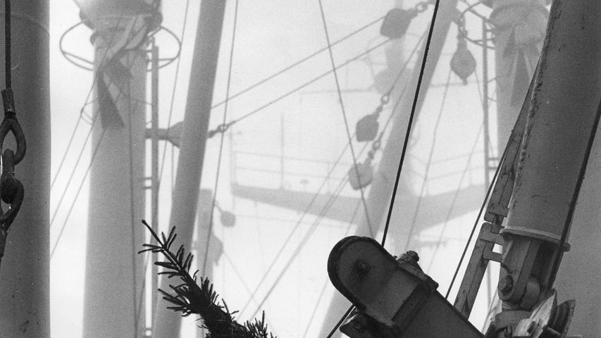 Ein Seemann klettert in das Gewirr der Masten und Ladebäume auf dem Hapag-Lloyd-Motorschiff „Nürnberg“. Auf der Schulter trägt er einen Christbaum, der hoch über dem Deck aufgepflanzt wird. Hier geht es zum Kalenderblatt vom 24. Dezember 1970: Beim Fischfang vor Island.