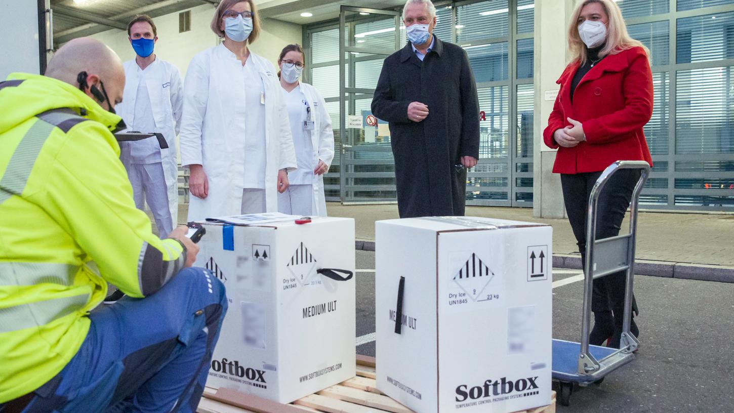 Erlangen: Bayerns Innenminister Joachim Herrmann und Gesundheitsministern Melanie Huml stehen neben Kartons mit den ersten Dosen Corona-Impfstoff für Bayern.
