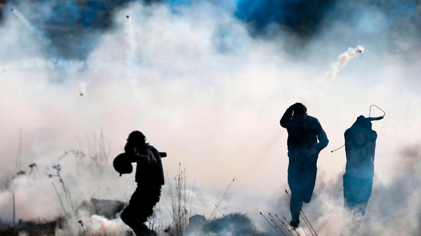 Palästinensische Demonstranten rennen vor Tränengasschwaden davon, die von israelischen Truppen abgegeben wurden. Sie hatten zuvor gegen die israelische Besiedlung der Ortschaft Deir Jarir im Westjordanland protestiert.
