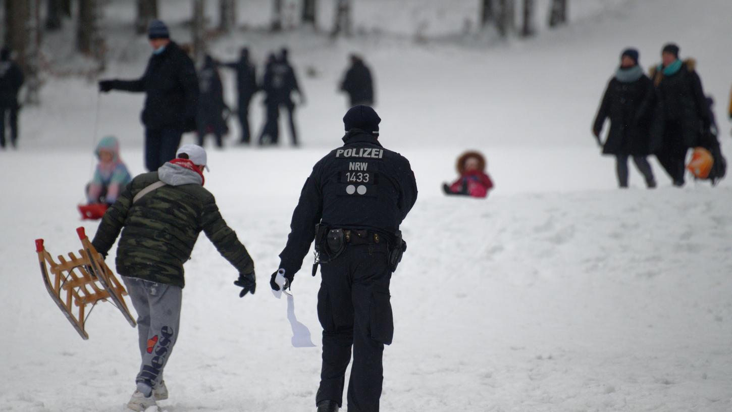 Ein Polizist fordert auf einer Piste im Skigebiet in Winterberg die Besucher zum Gehen auf.
