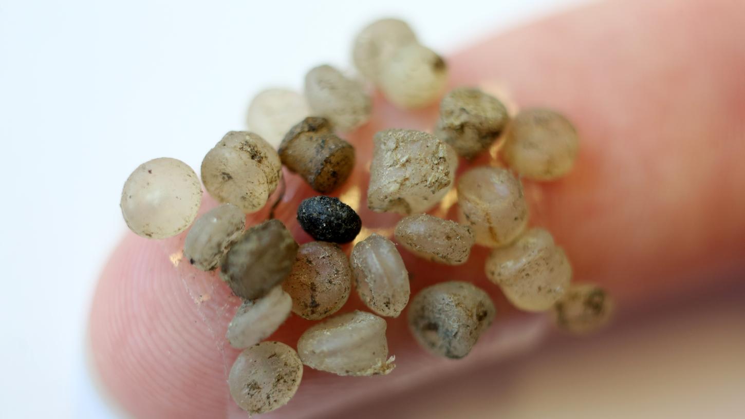 Zugemüllte Ozeane: Mikroplastik-Teilchen aus dem Meer kleben an einem Klebestreifen an einem Finger.