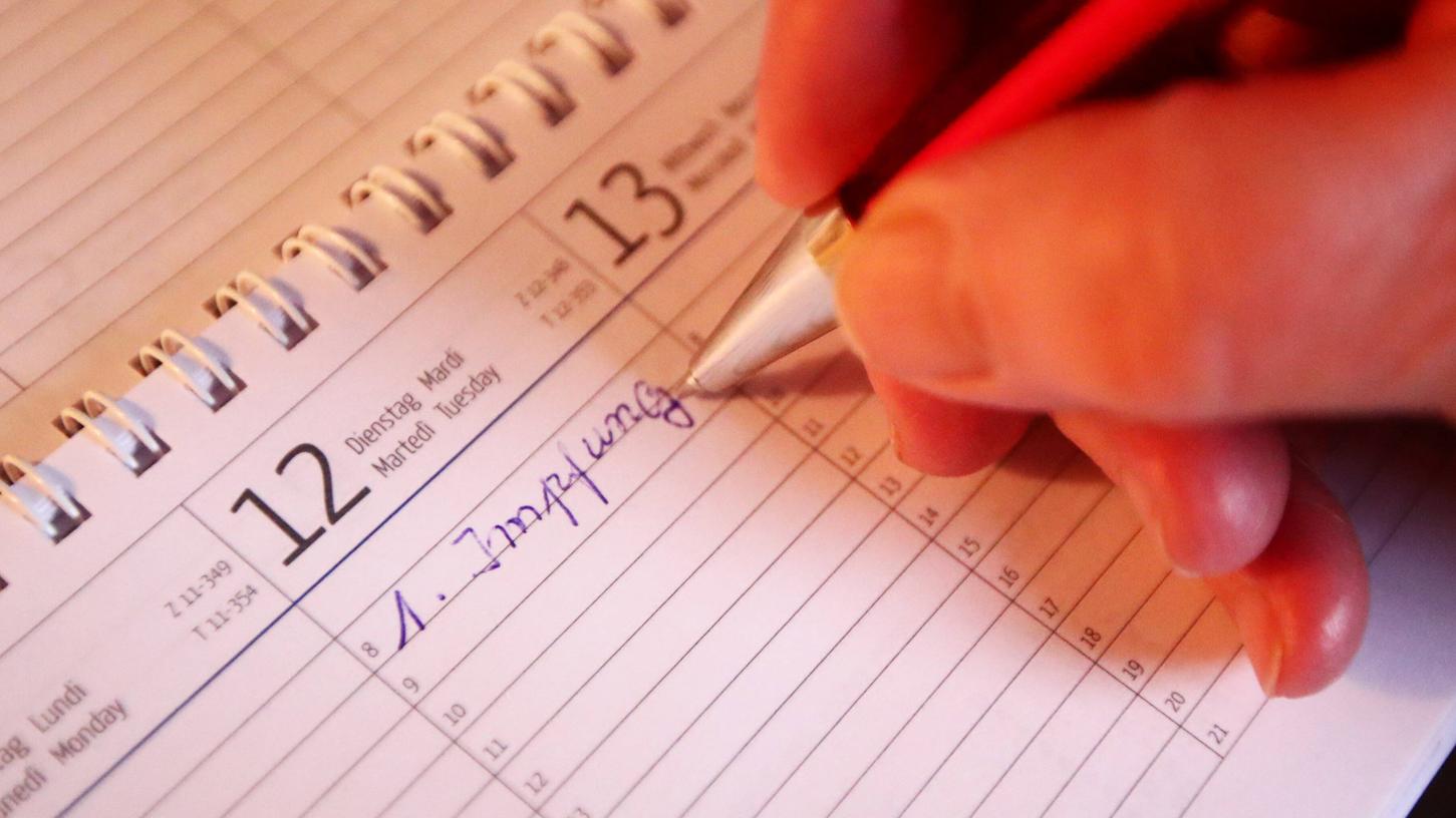 Eine Frau trägt ihren Impftermin in den Kalender ein. Eine Frau trägt ihren Impftermin in den Kalender ein.