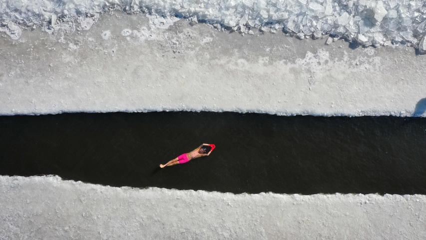 In Shenyang in der chinesischen Republik Lianoing schwimmt ein Mann in einem Becken, das in das Eis eines gefrorenen Sees geschnitten wurde.