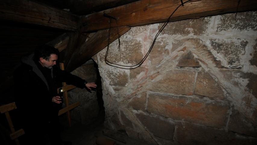 Hier sieht man schön: Pfarrer Wilfried Lechner-Schmidt deutet auf die alte romanische Dachkante, daneben ist die Vergrößerung aus dem 15. Jahrhundert zu erkennen.