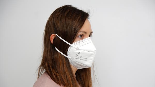 Alle, die ihre Haare gerne offen tragen, sollten darauf achten, sie über die FFP2-Maske sowie die Spannbänder zu legen - und nicht darunter. Ansonsten liegt die Maske an den Wangen nicht richtig an.