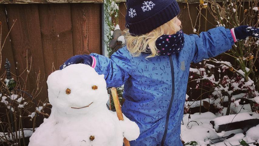 Die junge Dame auf dem Foto freut sich über ihren ersten Schneemann. 