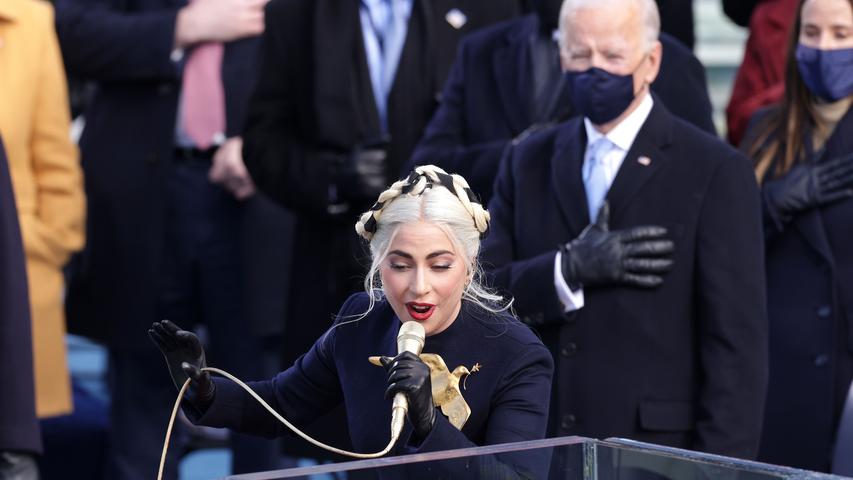 Die Popsängerin Lady Gaga hat die Ehre, die Nationalhymne zu singen. Im Hintergrund: Joe Biden, der kurz vor seiner Vereidigung steht. 