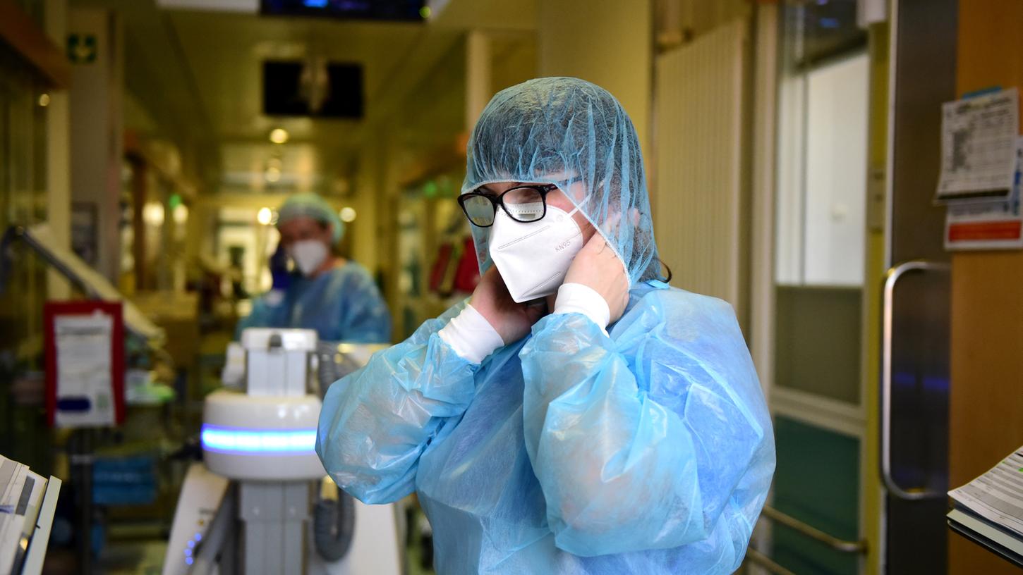 Eine Pflegekraft bereitet sich auf der Intensivstation darauf vor, ein Patientenzimmer zu betreten.