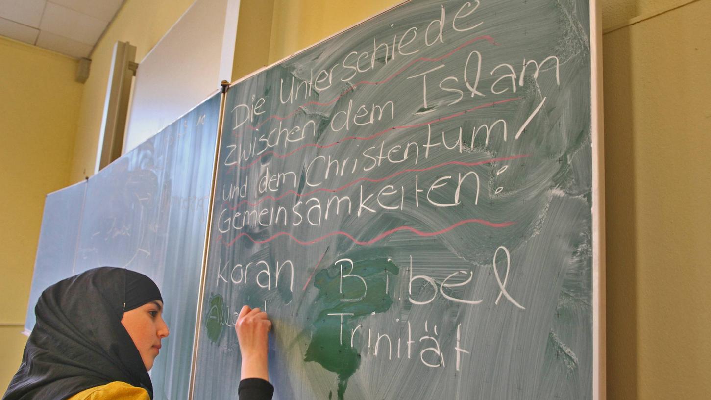 Eine muslimische Schülerin schreibt im Islamunterricht Begriffe an die Tafel. In Bayern wird das Fach bisher an über 360 Schulen unterrichtet.