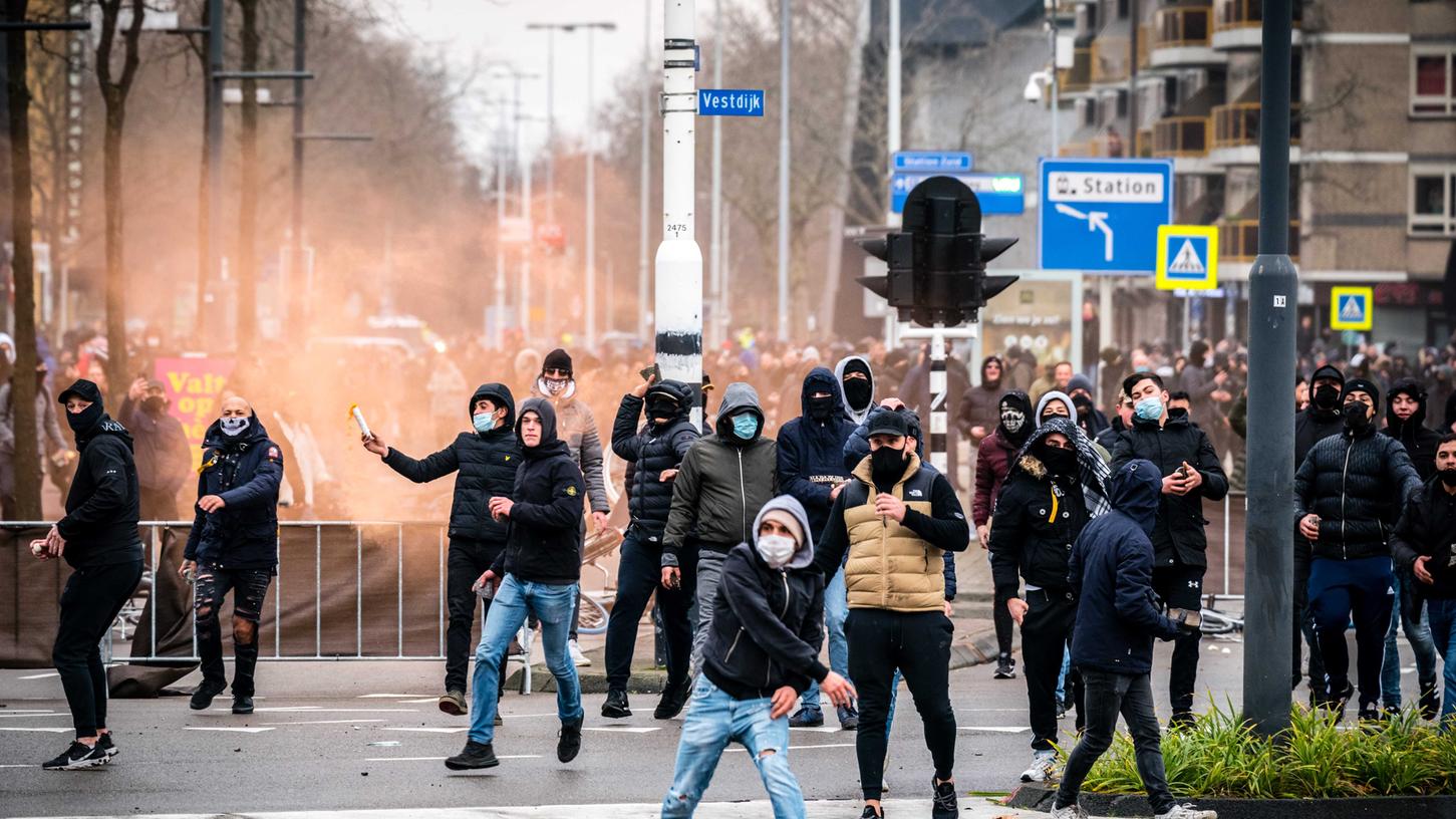 Niederlande, Eindhoven: Demonstranten werfen auf einer Straße mit Steinen. Mehrere hundert Menschen haben vor dem Bahnhof von Eindhoven gegen die aktuelle Corona-Politik demonstriert.