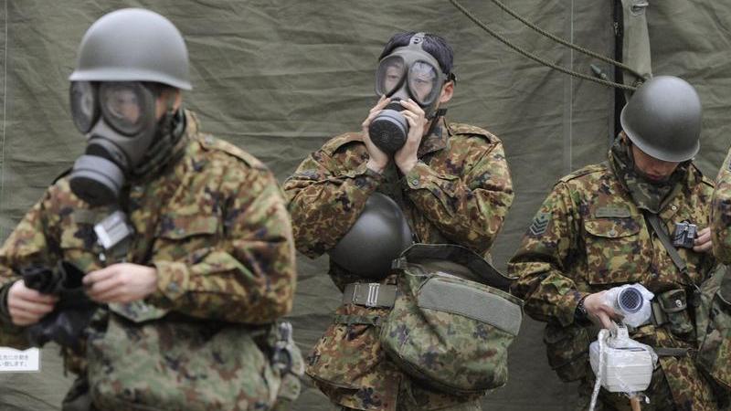 Militär und Hilfskräfte versuchen sich bei ihren Arbeiten im kontaminierten Gebiet um Fukushima provisorisch zu schützen.